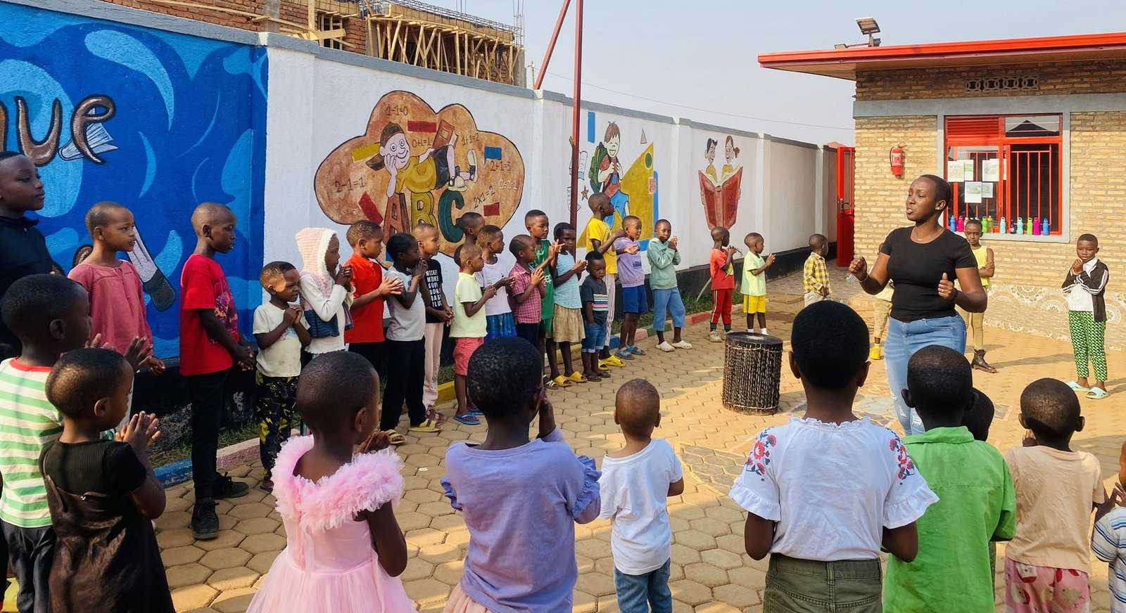 Les enfants applaudissent en cercle autour d'un tambour pendant la danse